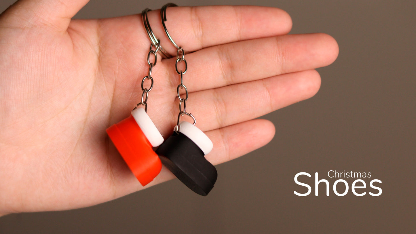 a hand holding a pair of black, white, and orange rubber shoes