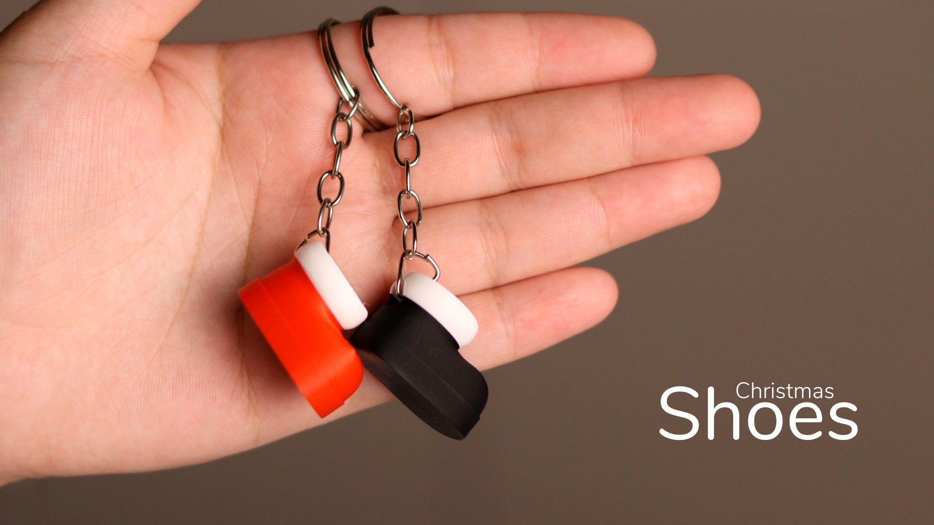 a hand holding a pair of black, white, and orange rubber shoes