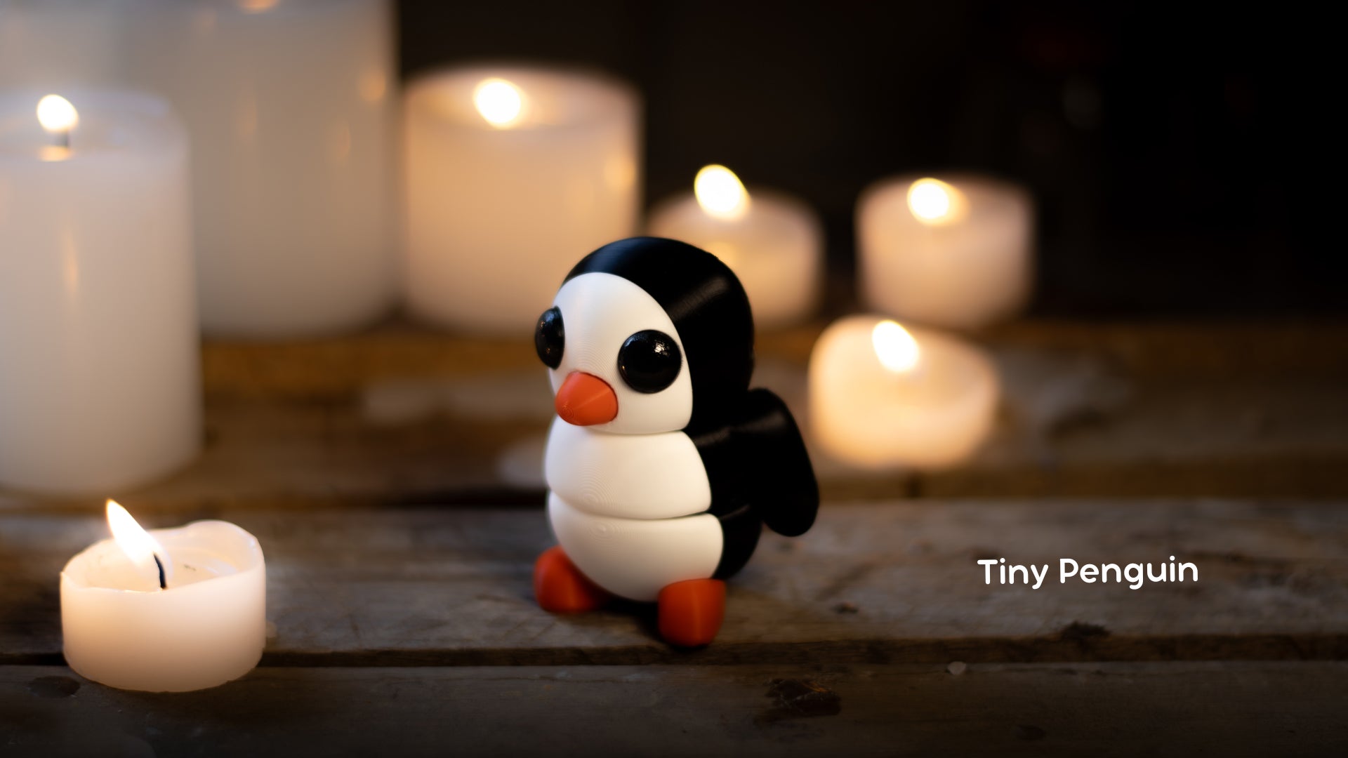 a small penguin sitting next to a lit candle