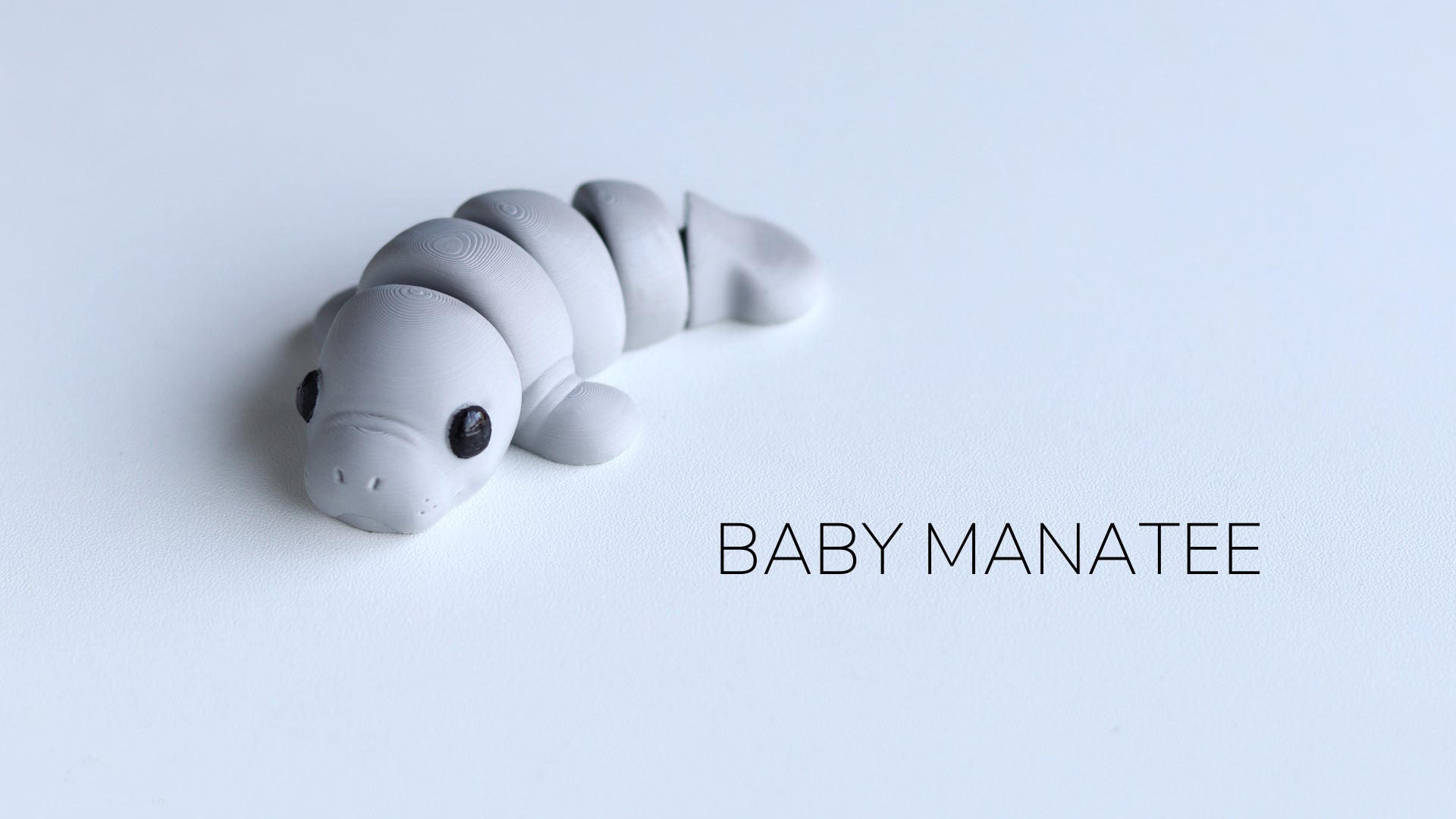 a baby manatee toy laying on top of a white surface