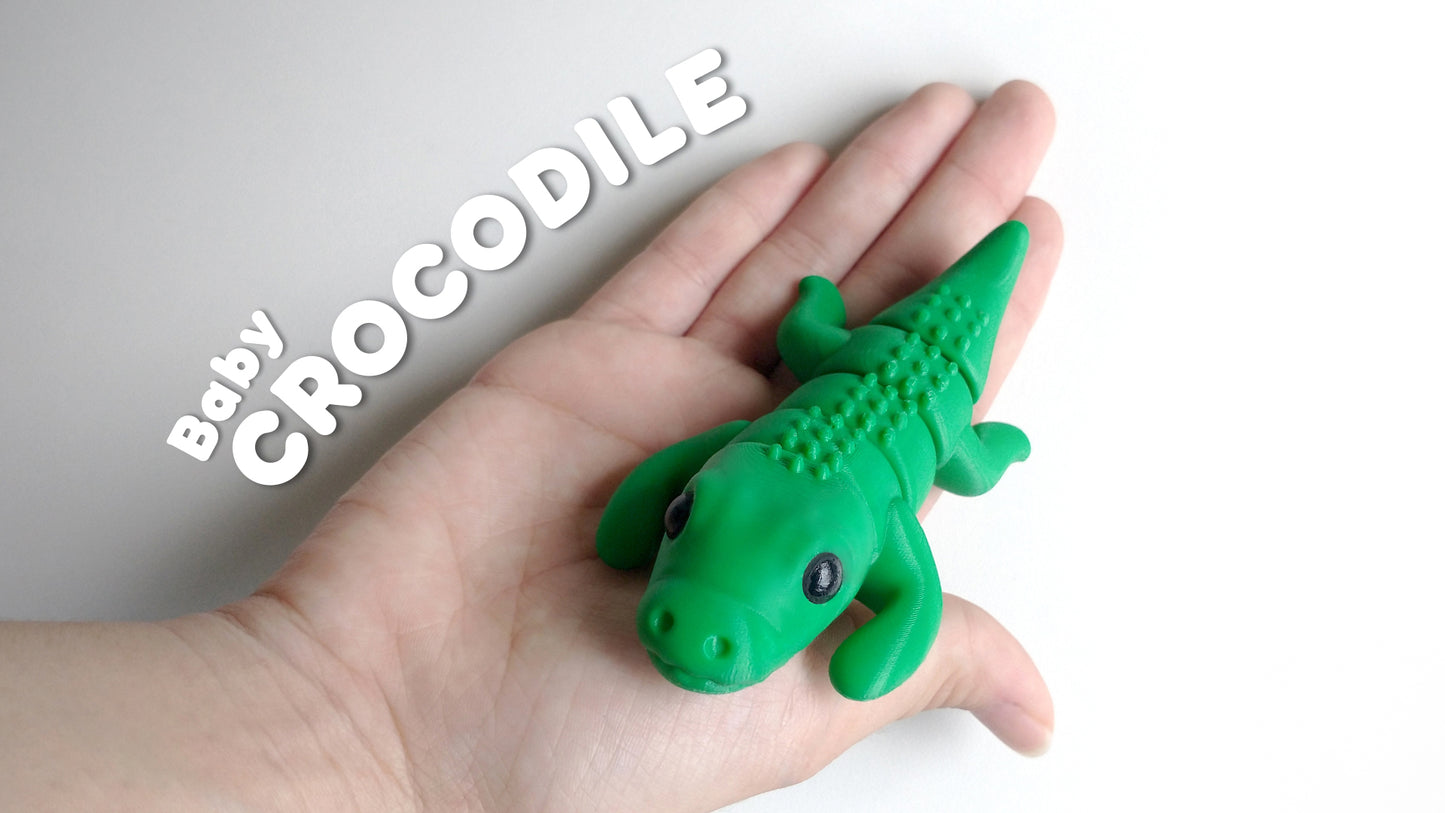 a hand holding a green toy alligator in it's palm