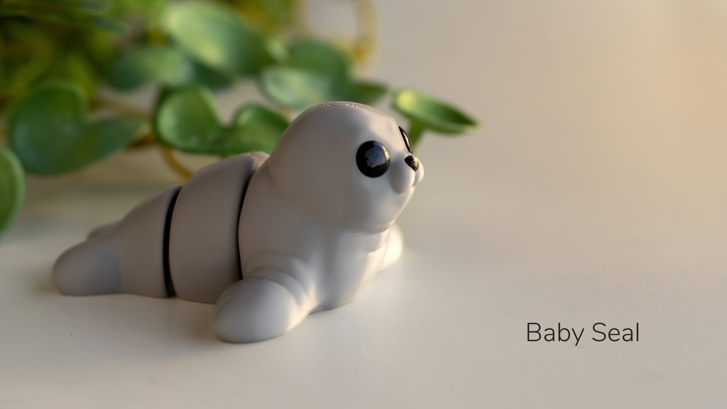 a baby seal toy laying on a table next to a plant