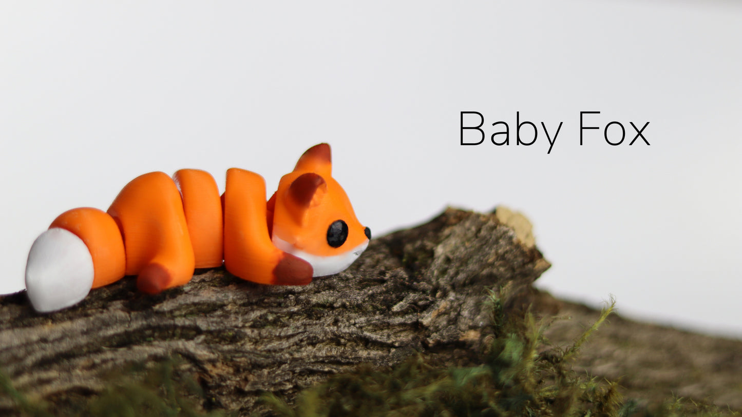 a baby fox figurine sitting on top of a tree branch