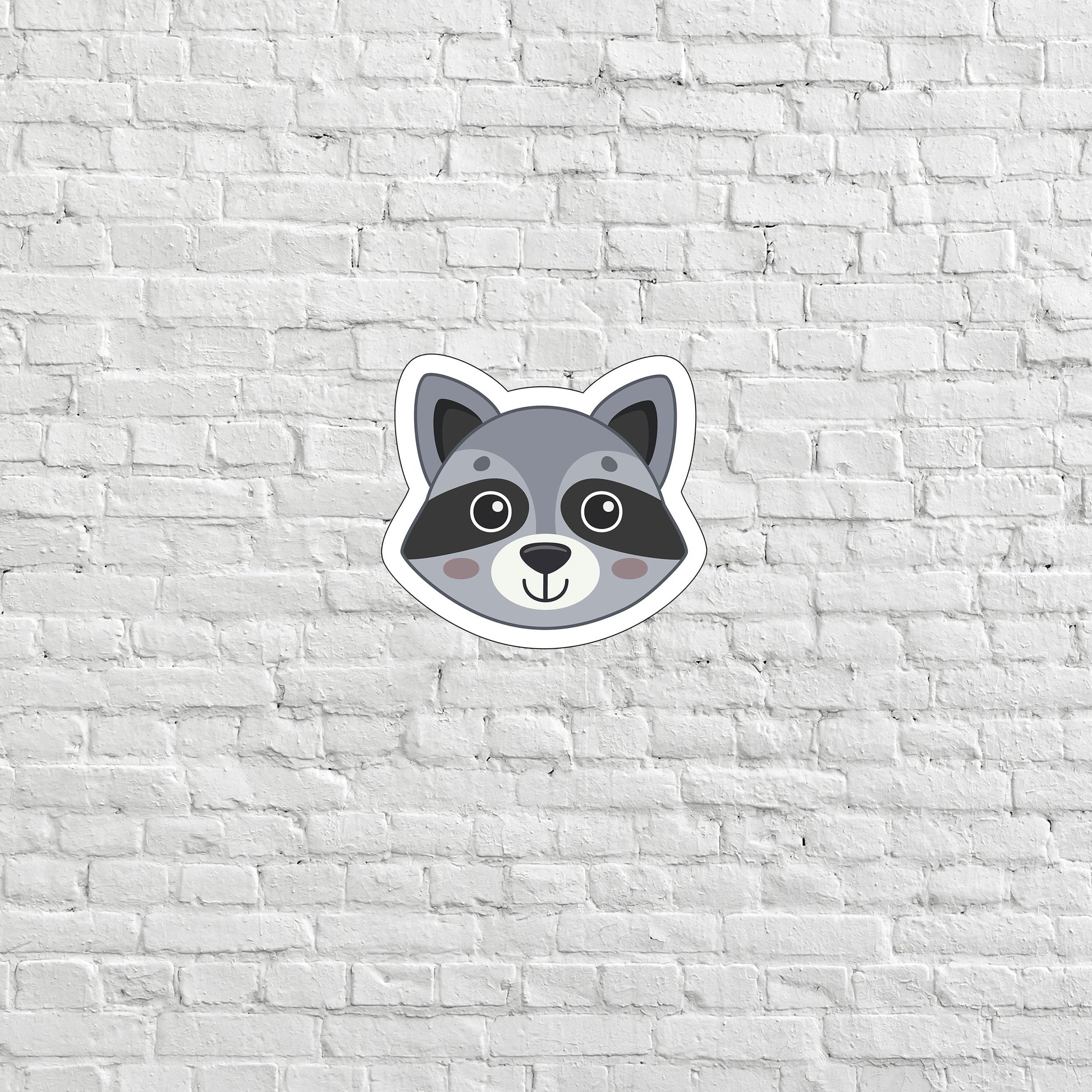 a raccoon sticker on a white brick wall