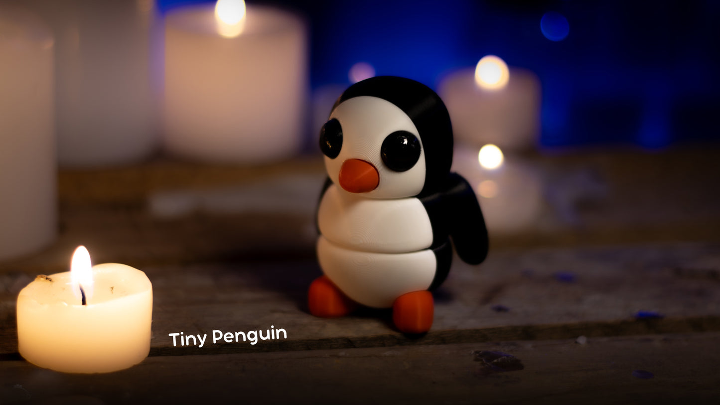 a small penguin sitting next to a lit candle