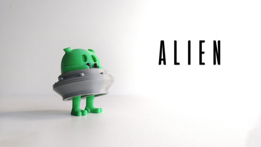 a green toy holding a white object with the word alien on it