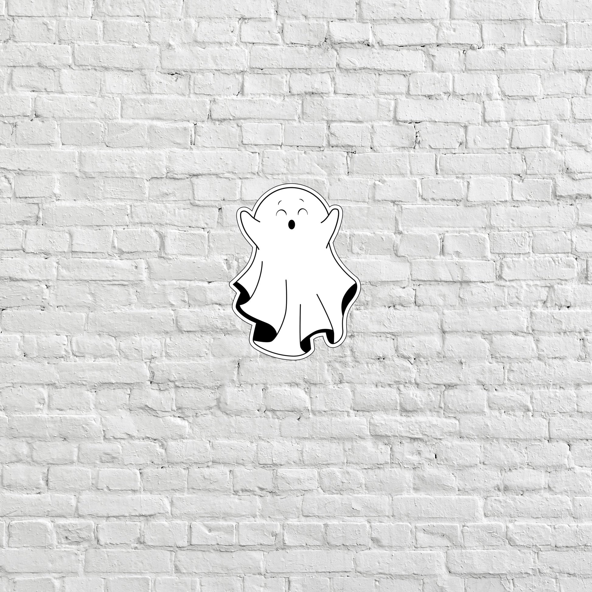 a sticker of a ghost on a white brick wall