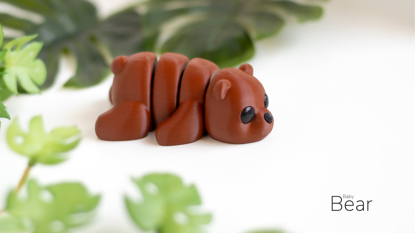 a brown bear figurine sitting next to a plant