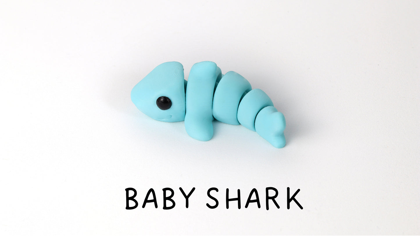 a blue baby shark toy laying on top of a white surface