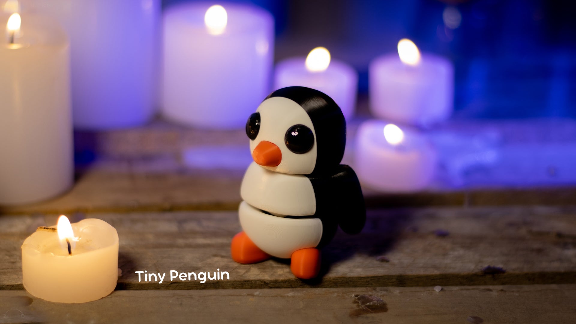 a small penguin sitting next to a lit candle