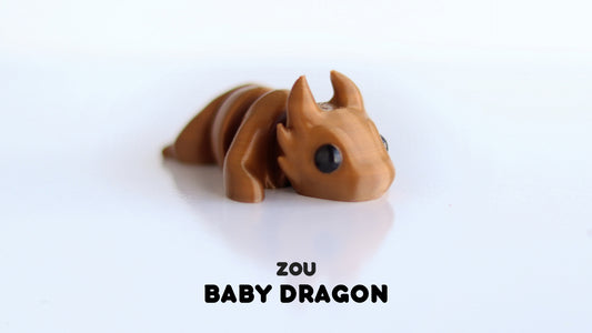 a baby dragon toy laying on top of a white table