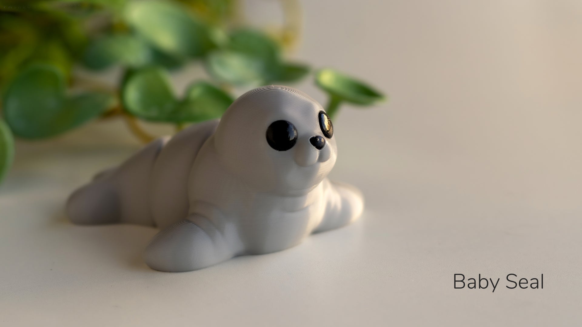 a small toy seal sitting next to a plant