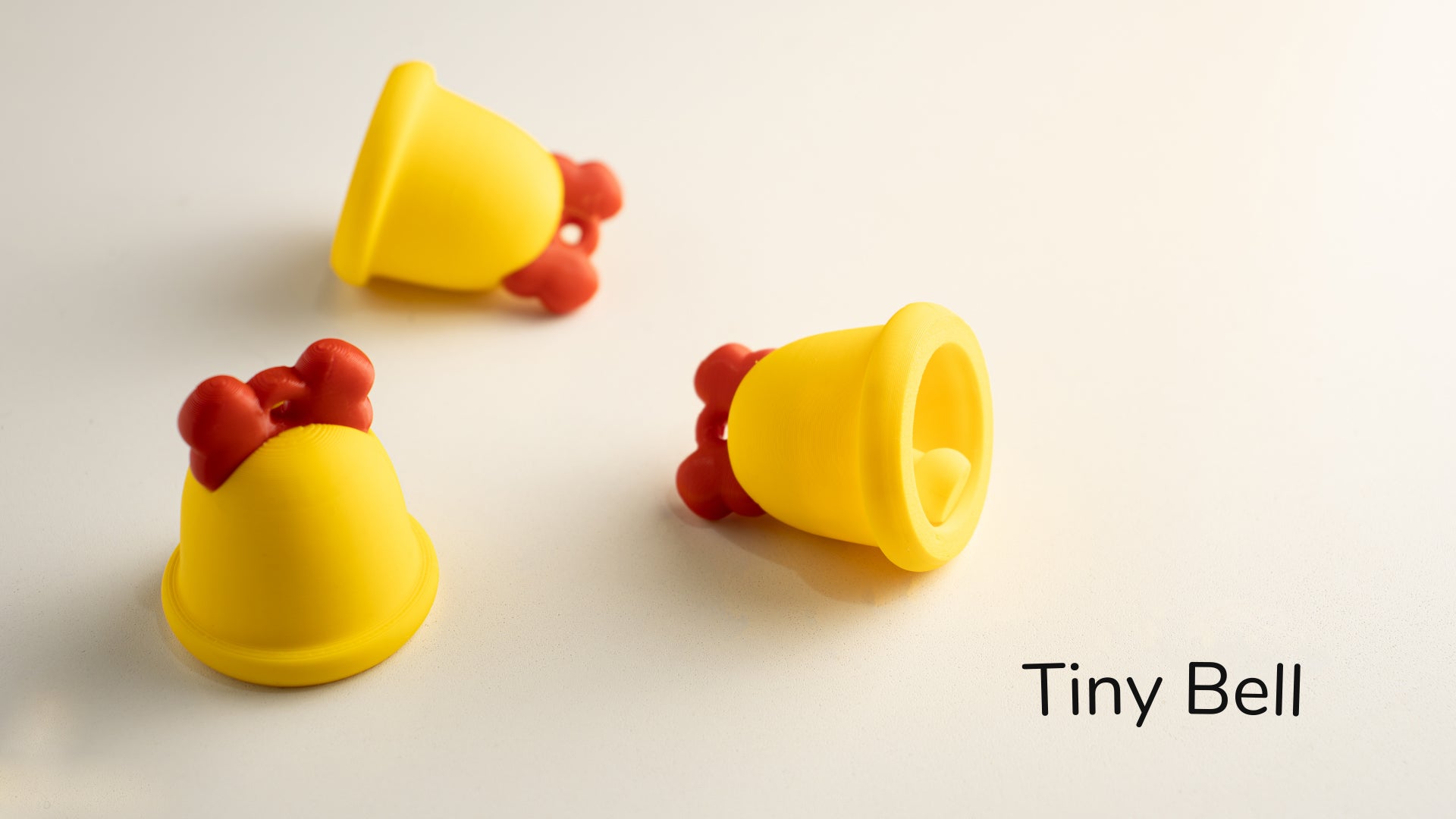 three yellow toy bells sitting on top of a white table