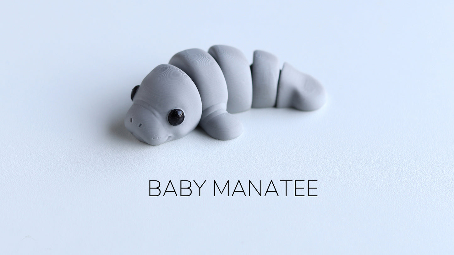 a baby manatee toy laying on top of a white surface