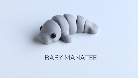 a baby manatee toy laying on top of a white surface