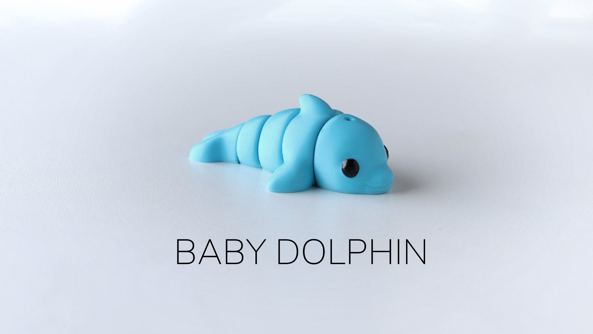 a baby dolphin toy laying on top of a white surface