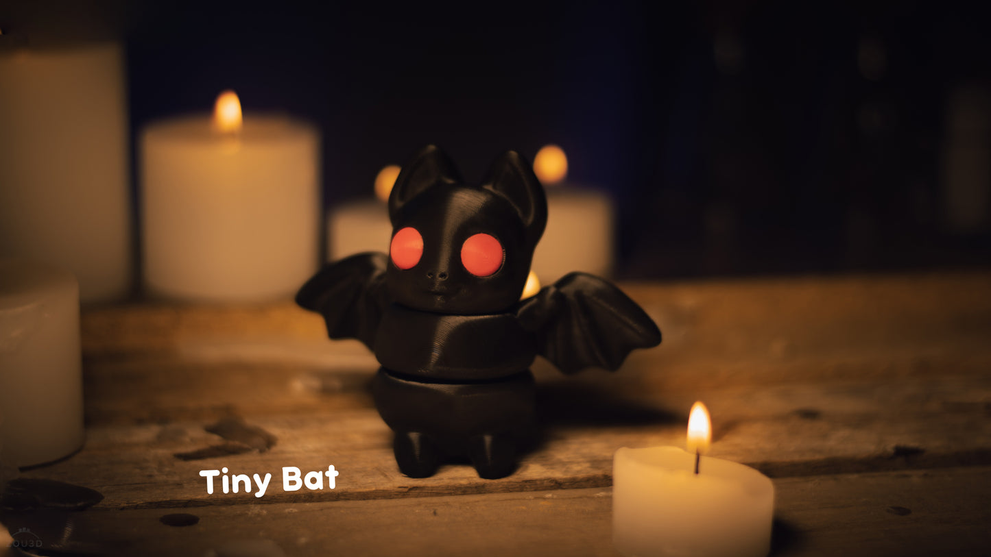 a small toy bat sitting next to a lit candle