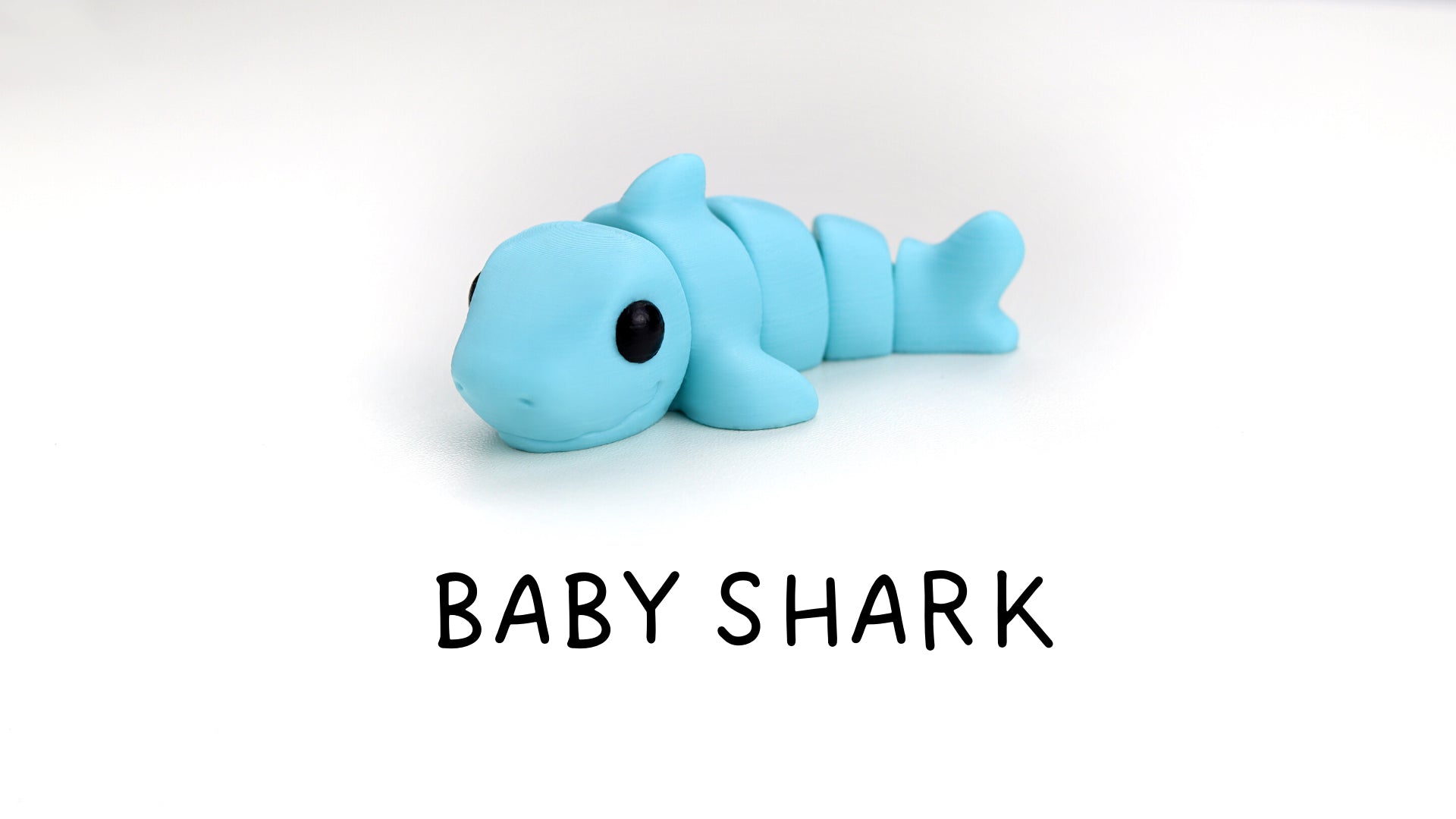 a baby shark toy laying on top of a white surface