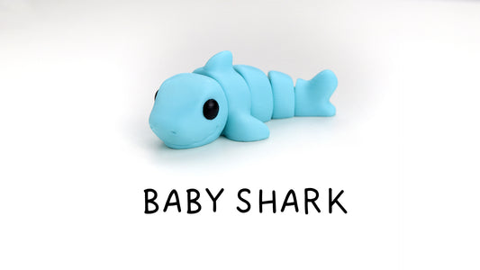 a baby shark toy laying on top of a white surface