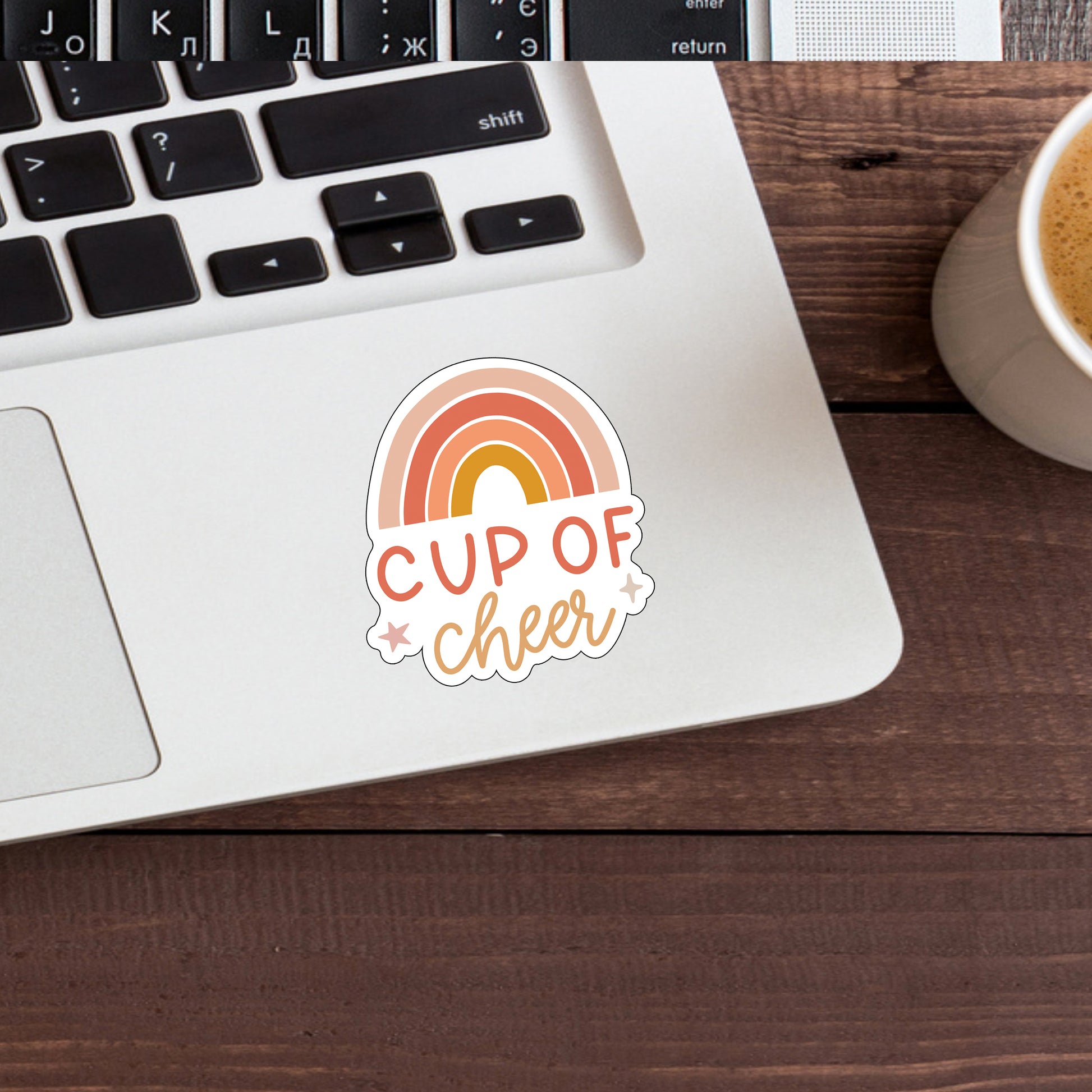 a cup of cheer sticker next to a laptop