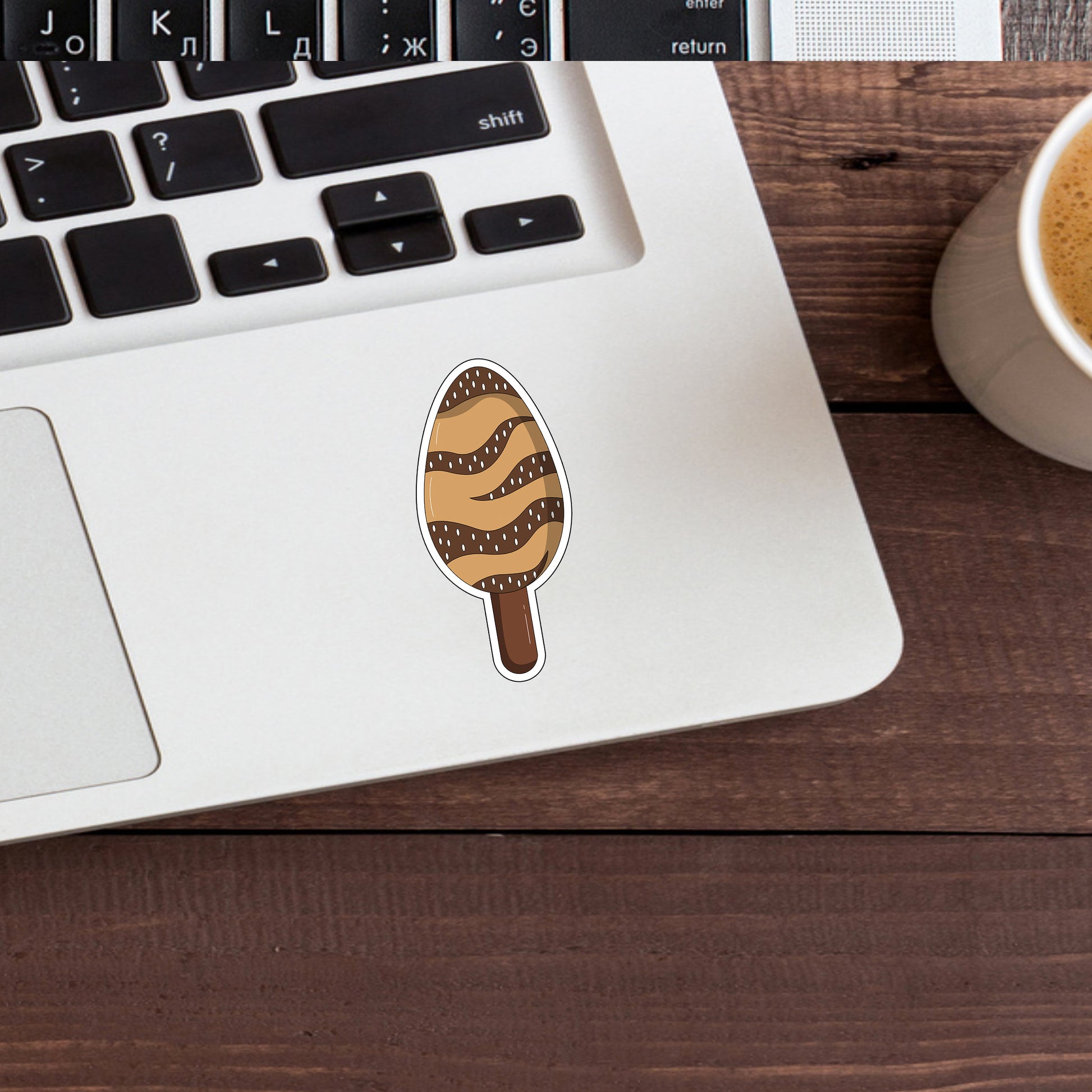 a cup of coffee next to a laptop with a sticker on it