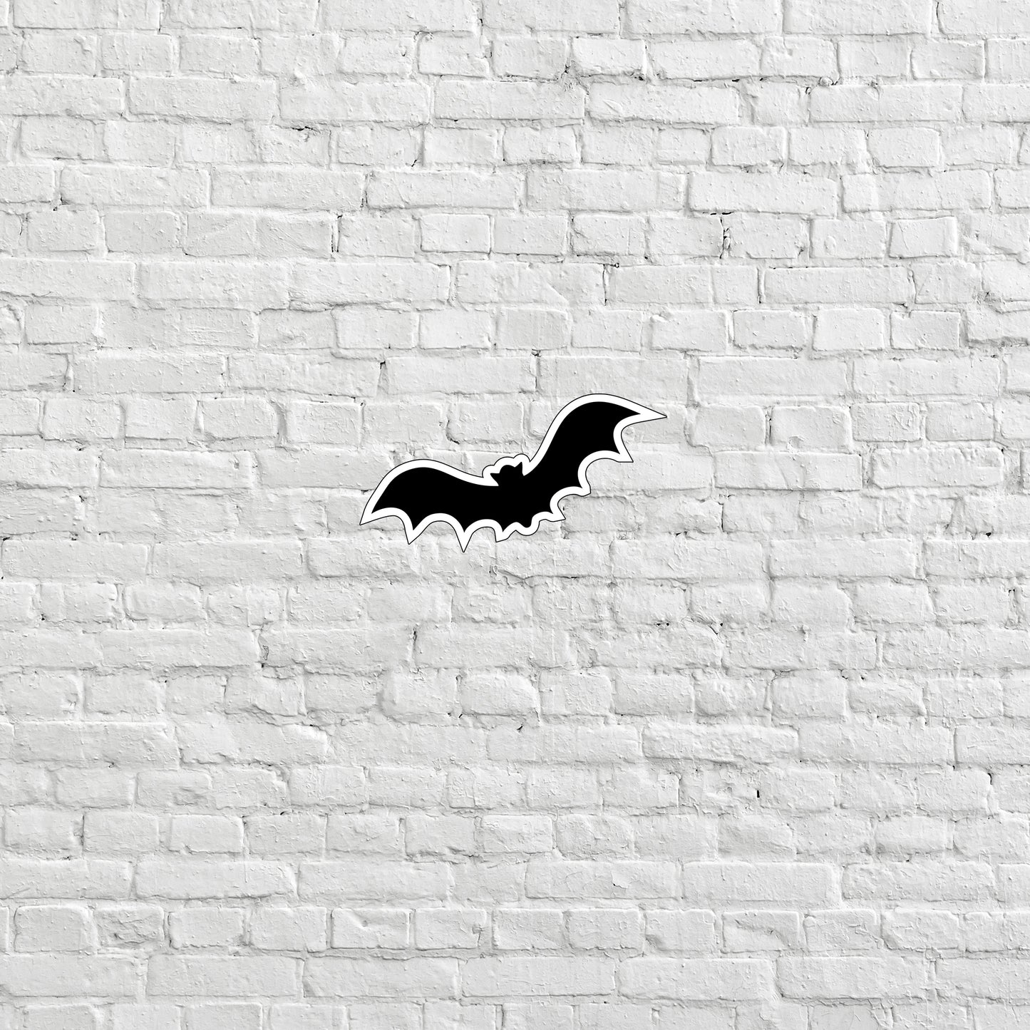 a black bat sticker on a white brick wall