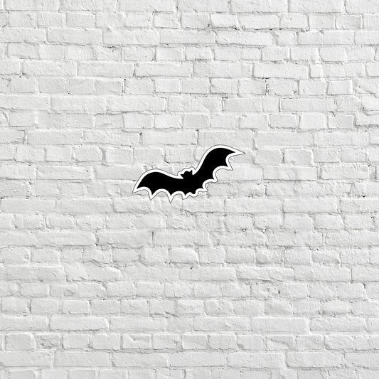 a black bat sticker on a white brick wall